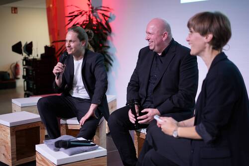 Drei Menschen sitzen nebeneinander und diskutieren. 